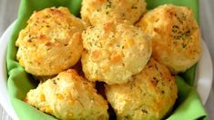 a white bowl filled with cheesy biscuits on top of a green napkin