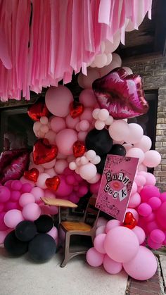 pink, black and white balloons are hanging from the ceiling