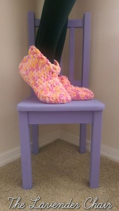 a purple chair with a pair of crocheted slippers on it