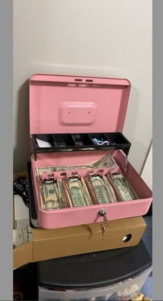 a pink suitcase filled with money sitting on top of a table