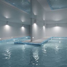 an indoor swimming pool with blue and white tiles on the walls, surrounded by water features