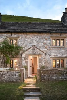 a stone house with steps leading up to the front door and entry way, at dusk