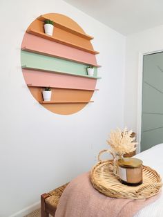 a room with a bed, wicker basket and plant on the wall next to it