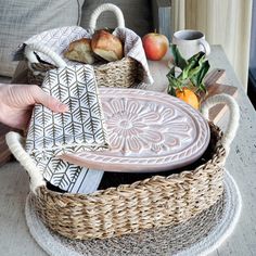 a person is holding a basket with bread and fruit in it on a coffee table