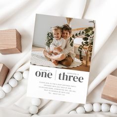 two children sitting next to each other on top of a white blanket with wooden blocks