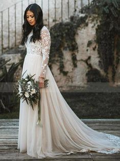 a woman in a wedding dress standing on a wooden floor holding a bouquet and looking at the camera