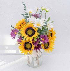 a bouquet of sunflowers and daisies in a vase