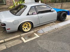 a gray car with yellow rims parked on the street