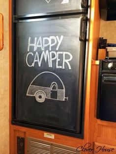 a happy camper chalkboard on the side of a refrigerator in a kitchen area