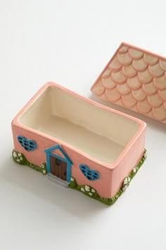 there is a small pink box with a blue house on the front and a smaller one in the back