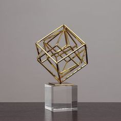 a gold sculpture sitting on top of a wooden table next to a gray wall in the background