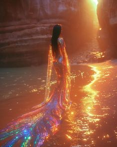 a woman is standing in the water wearing a long dress with lights all over it