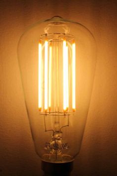 an old fashioned light bulb is lit up in the dark with some dim lights on it