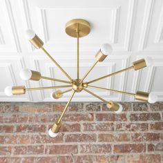 a chandelier hanging from the ceiling in a room with brick walls and white painted ceilings