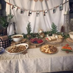 a table topped with lots of food next to a white cloth covered wall behind it