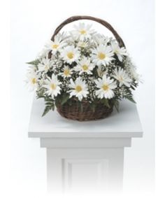 a basket filled with white daisies sitting on top of a table