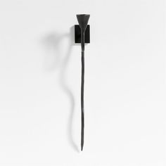 a black object is hanging on the wall and it looks like a toothpick