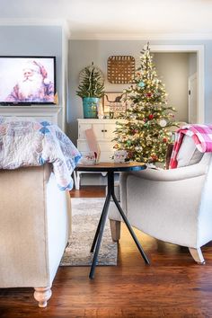 a living room with a christmas tree in the corner and two chairs next to it