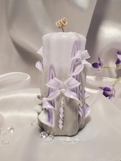 a candle with purple and white decorations on it