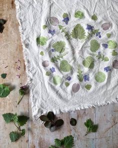 the table is covered with green leaves and purple flowers on white linen, which has been cut in half