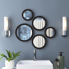 four circular mirrors mounted on the wall above a sink