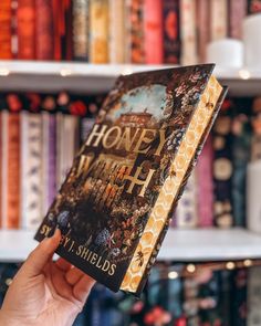 a person holding up a book in front of a bookshelf filled with books