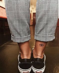 a person wearing black and white checkered pants with tattoos on their feet