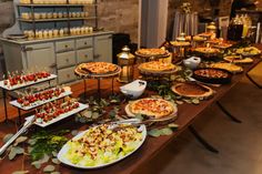 a table filled with many different types of food on plates and serving utensils