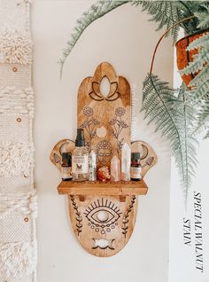 a wooden shelf with bottles on it next to a potted plant and wall hanging