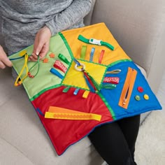 a person sitting on a couch with some toys in front of her and the child's hands