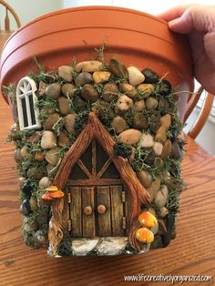 a clay pot with a house made out of rocks and moss