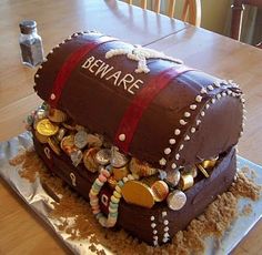 a cake made to look like a pirate chest with coins on the bottom and beware written on it