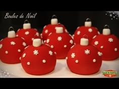 red ornaments with white flowers on them are sitting on a cake platter for someone's birthday