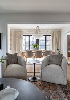 a living room with two chairs and a table in front of a large glass window