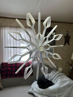 a white snowflake hanging from the ceiling in a room with a bed and window