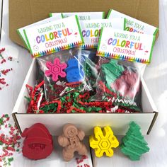 an open box filled with christmas cookies and candies on top of a white table