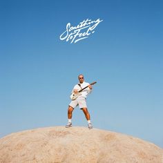 a man standing on top of a large rock with a tennis racquet in his hand