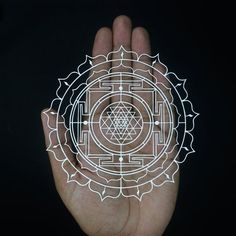 a person holding out their hand with an intricate design in the middle, on a black background