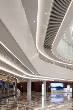 an empty lobby with marble flooring and white ceiling lights on either side of it