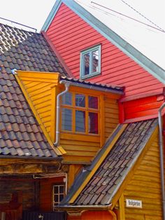 a row of houses with red and yellow shingles on the roof, one has an open window