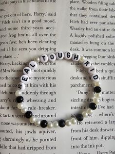 a beaded bracelet with words written in white and black beads on top of an open book