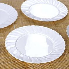 four white plates sitting on top of a bamboo mat