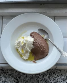 a bowl with some ice cream and a spoon in it on a tile counter top