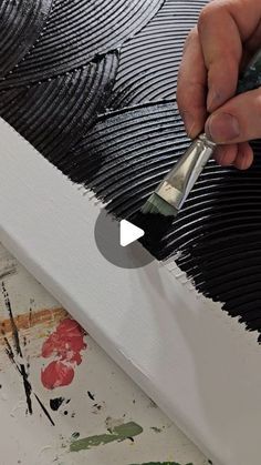 a person is using a brush to paint a piece of art with black and white stripes