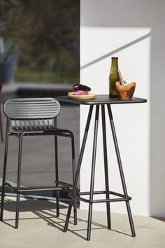 two stools sitting next to each other near a table with a bottle on it