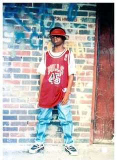 a young man standing in front of a brick wall