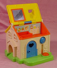 a small toy house with a mirror and door on the front, sitting on a pink background