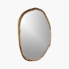 an oval shaped mirror with gold leaf decoration on the edges and bottom, against a white background