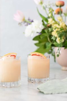 two glasses filled with drinks sitting on top of a table