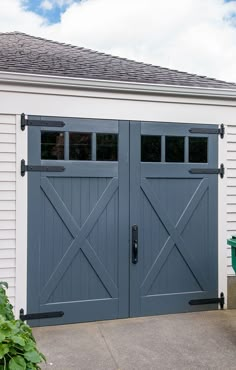 a garage with two double doors and a green trash can